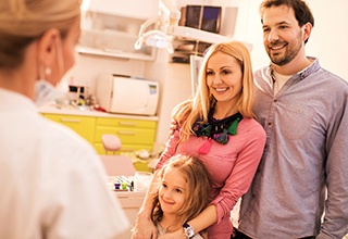 Smiling mother father and daughter in dentist's office