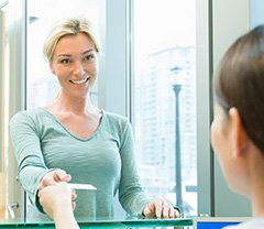 Woman handing her credit card to person at reception desk