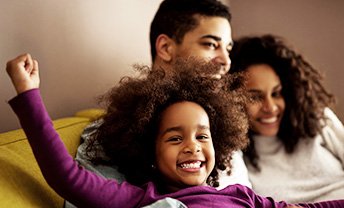 Smiling parents and daughter sitting on a couch