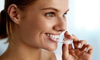 Woman placing an Invisalign tray over her teeth
