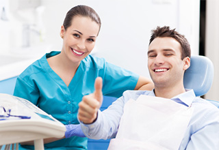 Man in dental chair giving thumbs up after tooth extractions in Inver Grove Heights