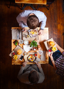 Three people sitting at a restaurant table with burgers
