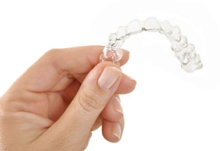 Hand holding an Invisalign clear aligner in Inver Grove Heights