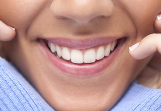 Close up of a person pointing to their smile