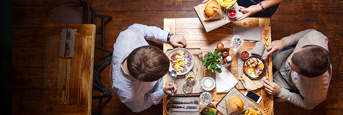 Group of people sitting at restaurant table with burgers