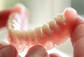 Hand holding a full denture