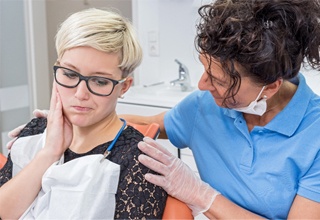 Dental patient holding her cheek in pain before root canal treatment in Inver Grove Heights