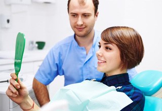 Woman holding mirror and smiling with brighter teeth